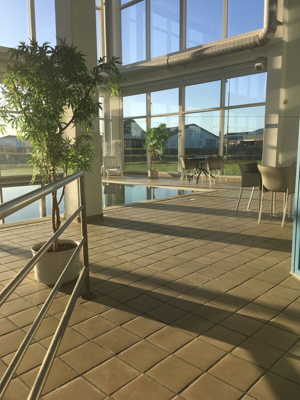 Una terraza con barandilla, plantas en macetas y mobiliario exterior.