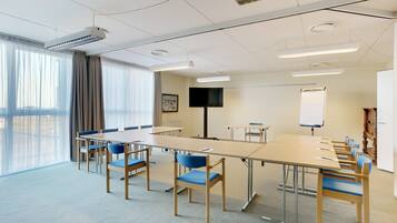A conference room with a long table, chairs, a TV, and a whiteboard.