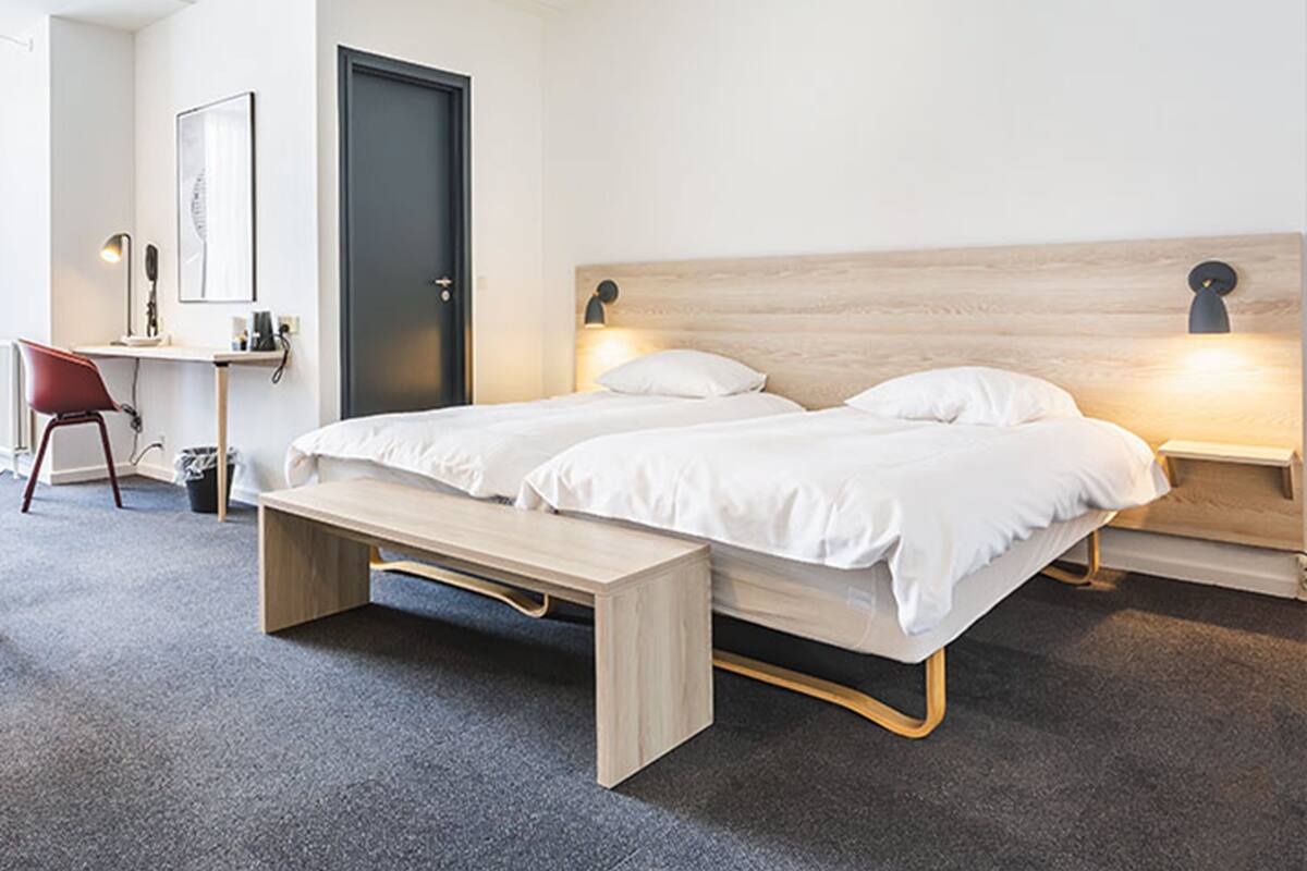 A modern bedroom with a bed, bedside tables, a desk, and a chair.
