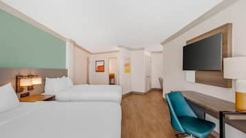 A hotel room with two beds, a desk, a chair, a TV, and a painting on the wall.