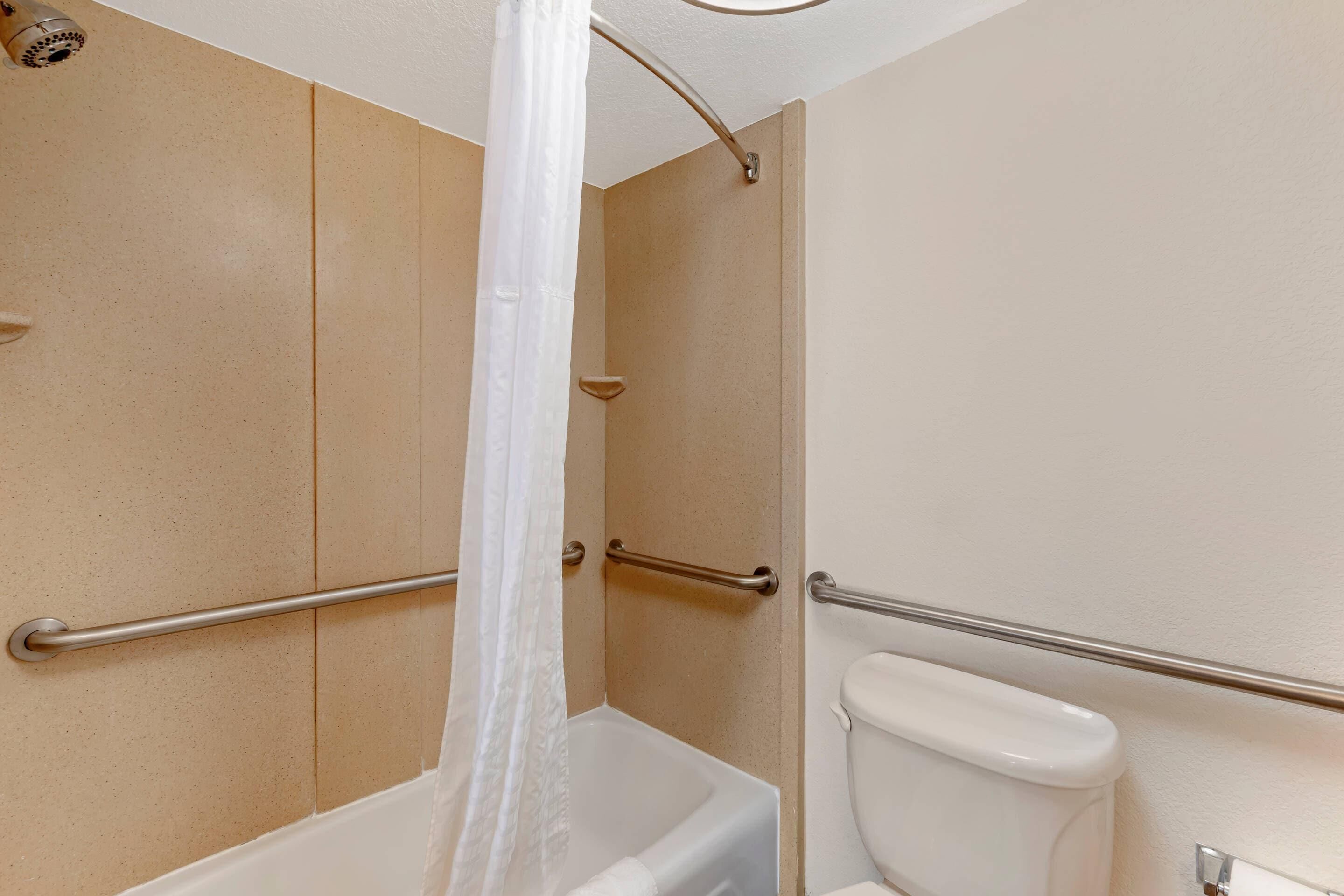 A bathroom with a bathtub, toilet, and a shower with a curtain.