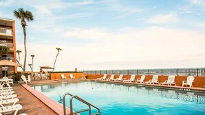 Ein Pool mit weißen Liegestühlen und einer Palme im Hintergrund.