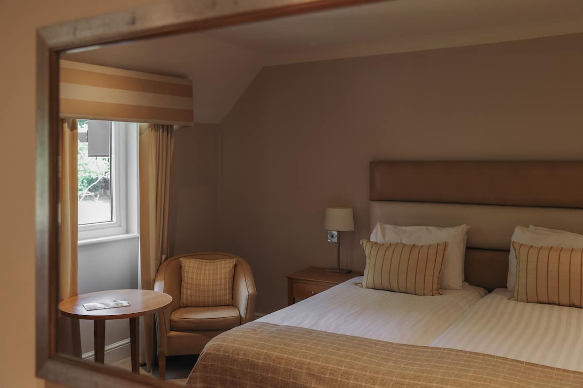 Una habitación de hotel con cama, una silla, una mesita y una mesita de noche.