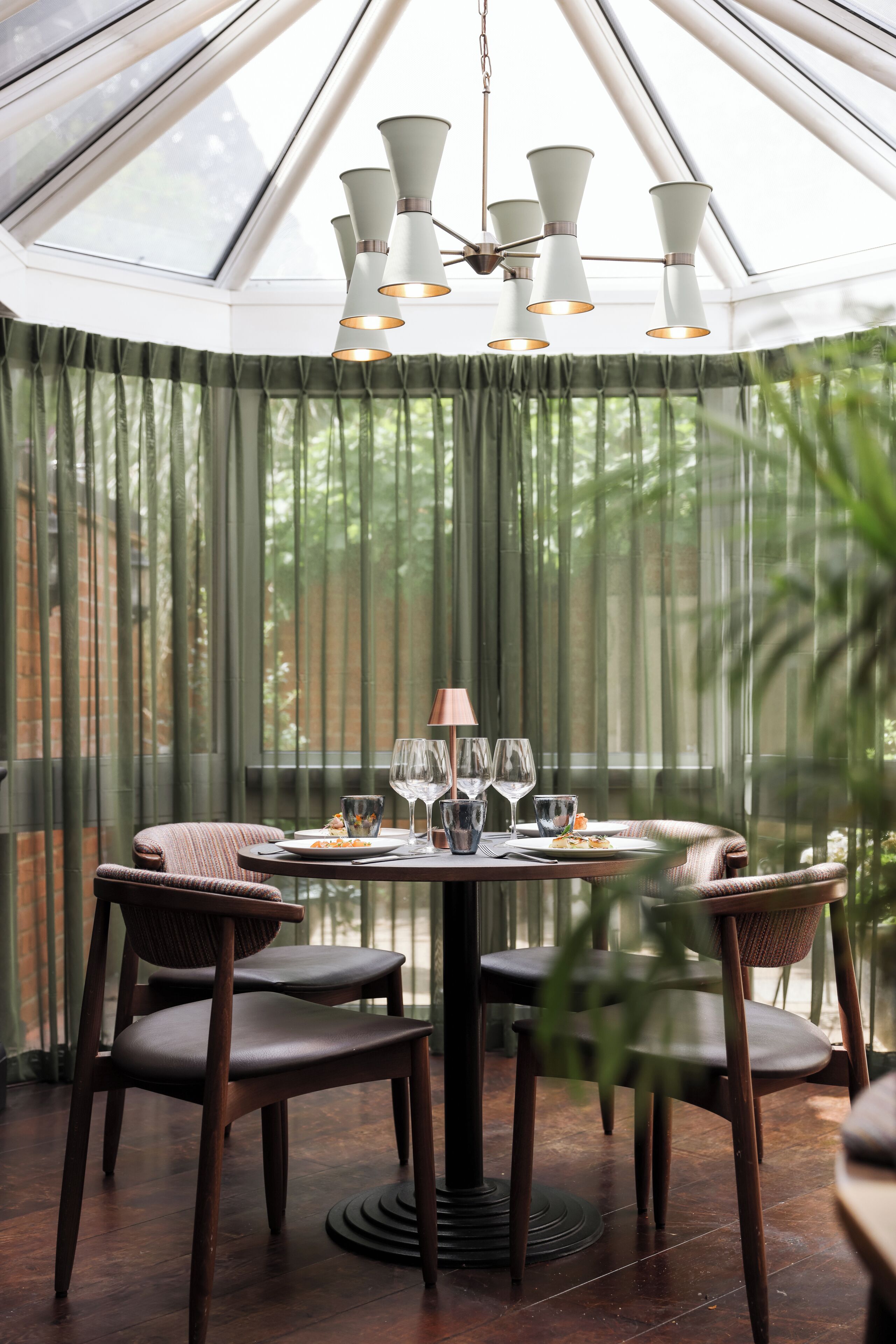 A dining area with a round table, four chairs, and a chandelier.