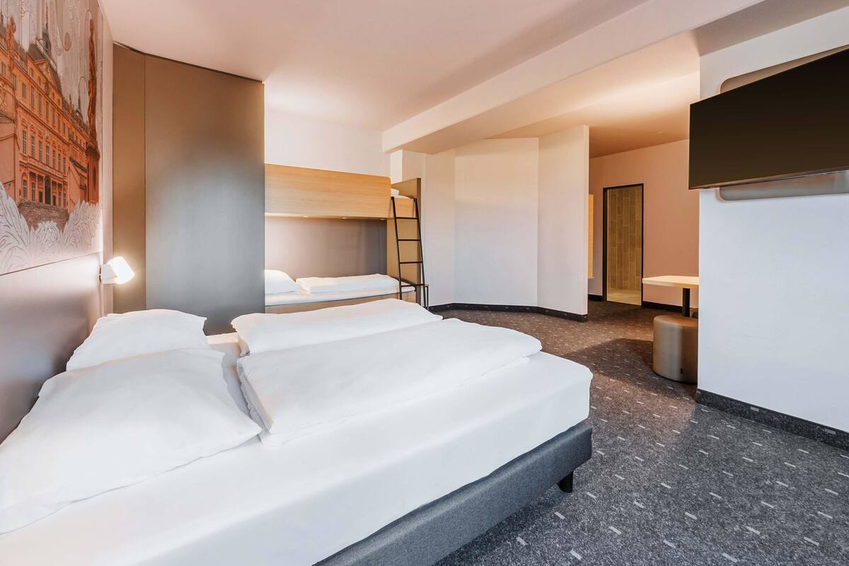 Une chambre d’hôtel avec deux lits, une échelle, une salle de bain et une fresque murale.