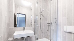 A modern bathroom with a glass-enclosed shower, a white sink, and a mirror. - B&B HOTEL Rastatt (Rastatt)