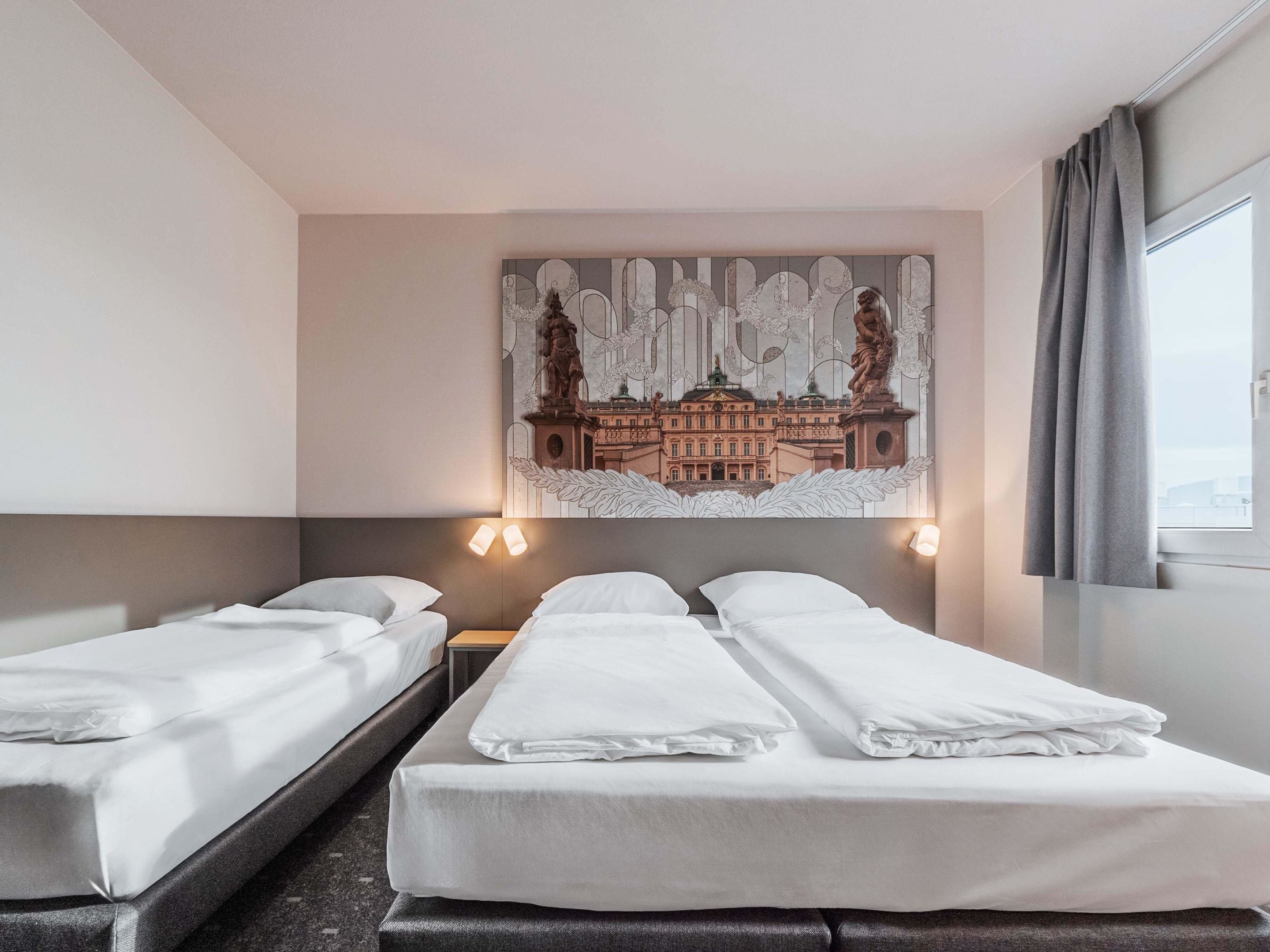 Ein Hotelzimmer mit zwei Einzelbetten, einer großen Wanddekoration und einem Fenster mit Vorhängen.