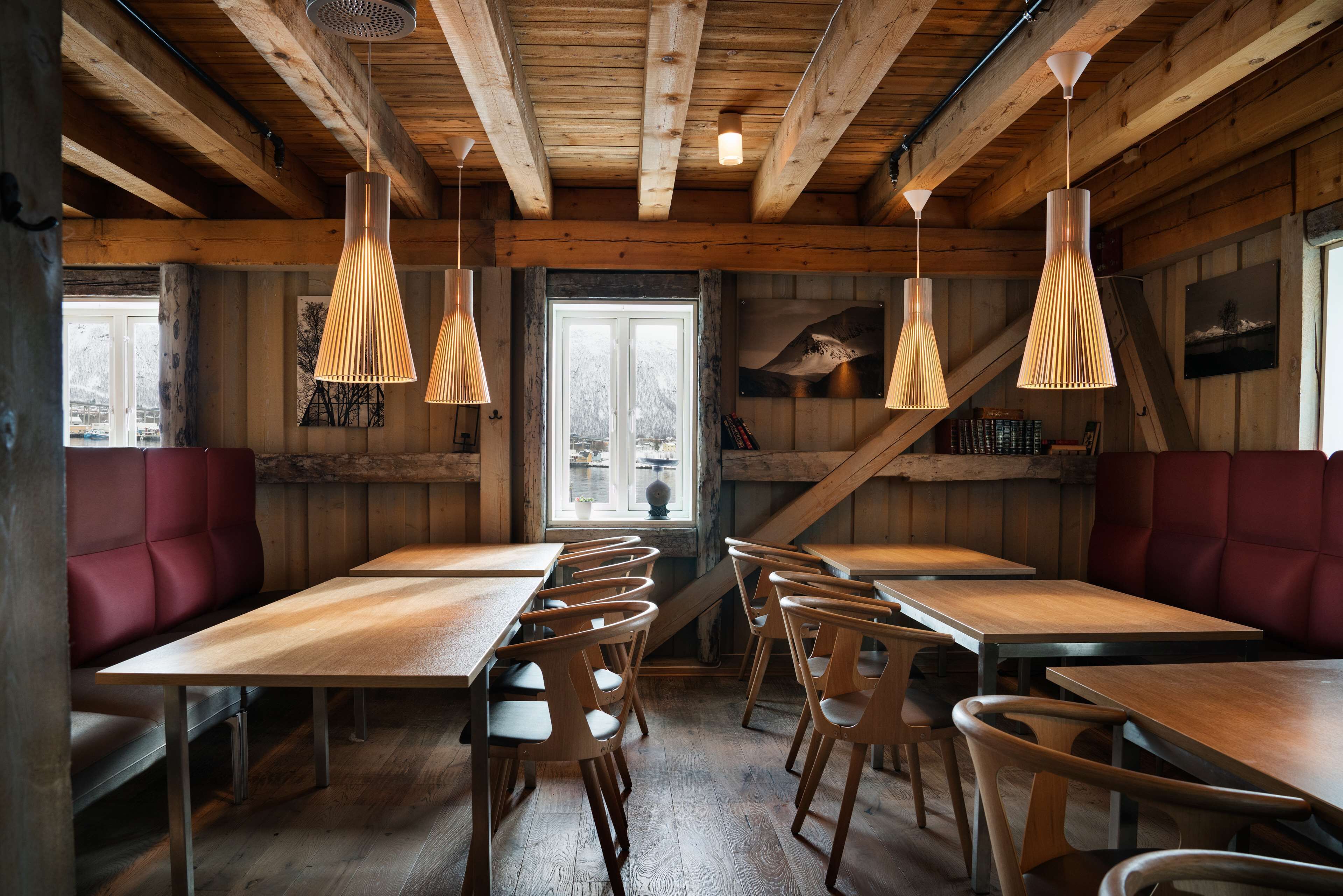 A wooden interior with high ceilings, wooden tables and chairs, and pendant lighting.