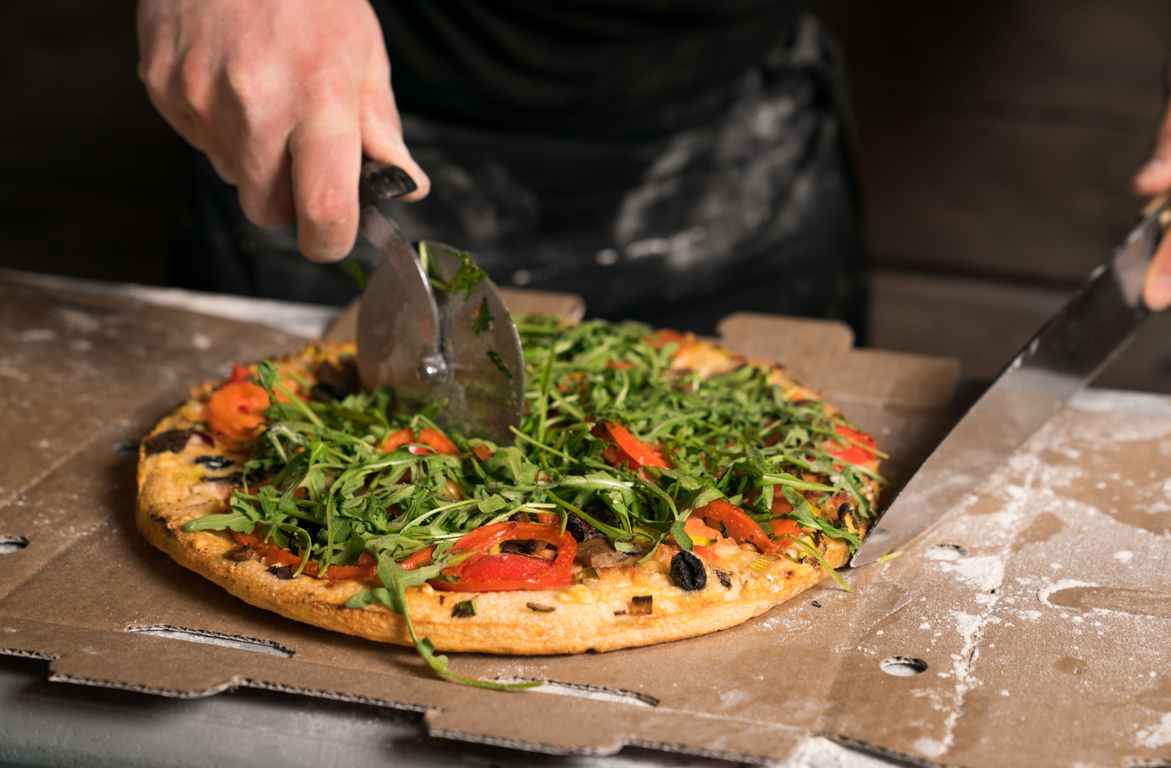 A pizza being cut with a large knife.