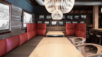 A cozy restaurant with wooden walls, red cushioned seating, and a large wooden table.