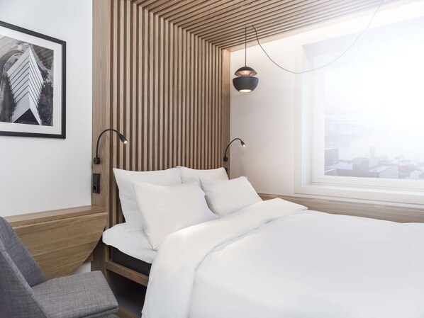 A modern hotel room with a bed, a desk, and a window with a city view. - Radisson Blu Hotel, Tromsø, A Verified Net Zero Hotel (Tromsø)