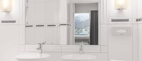 A modern bathroom with two large white sinks, a large mirror, and a view of a snowy landscape through the window.