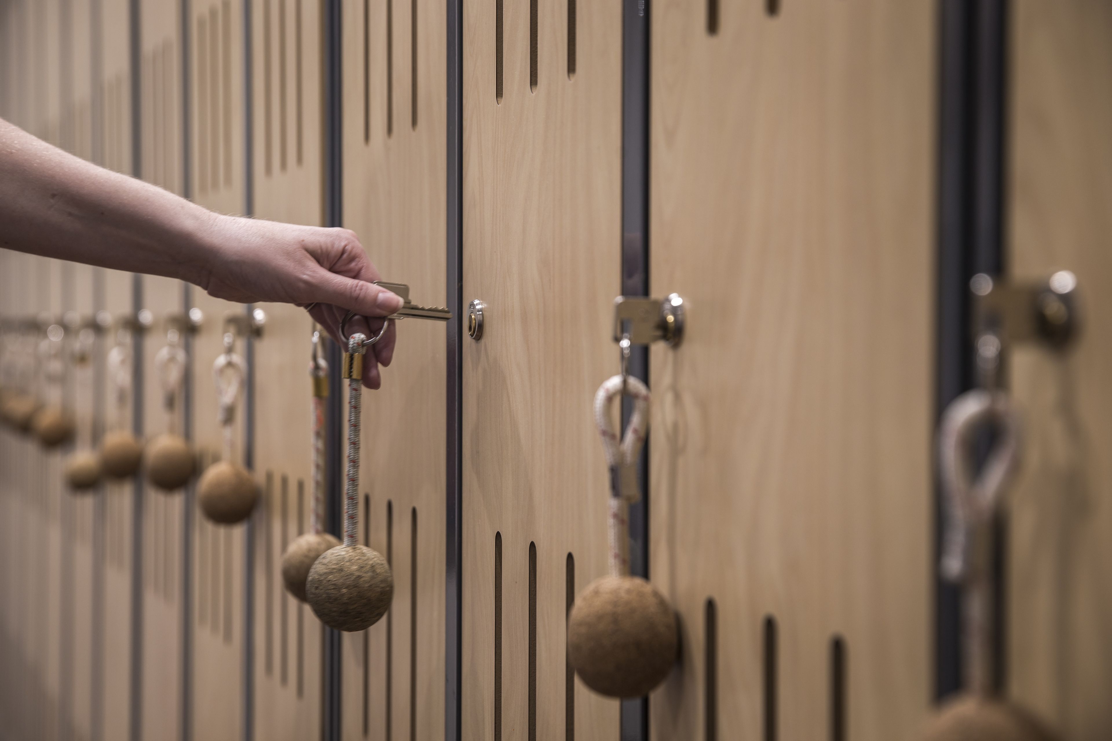 A hand unlocking a wooden locker with a key.