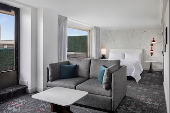 Relax in a stylish room with a comfortable bed, sofa, and desk area, offering a view of the surrounding cityscape and lush greenery. at Le Meridien Washington, D.C., The Madison