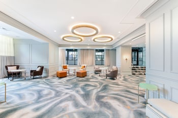 Experience the stylish lobby with a large carpet, comfortable seating, and a unique light fixture. at Le Meridien Washington, D.C., The Madison
