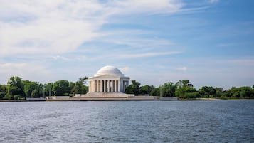 A large white building with a dome, surrounded by water and trees.