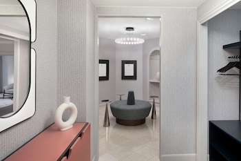 Relax in a serene bathroom with a large mirror, pink vanity, and comfortable seating area. at Le Meridien Washington, D.C., The Madison