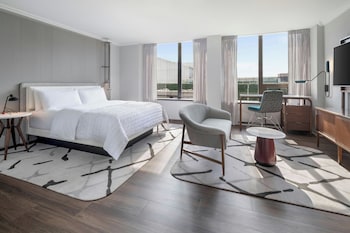 Relax in a spacious room with a large bed, seating area, and flat-screen TV, offering a view of the outdoors. at Le Meridien Washington, D.C., The Madison