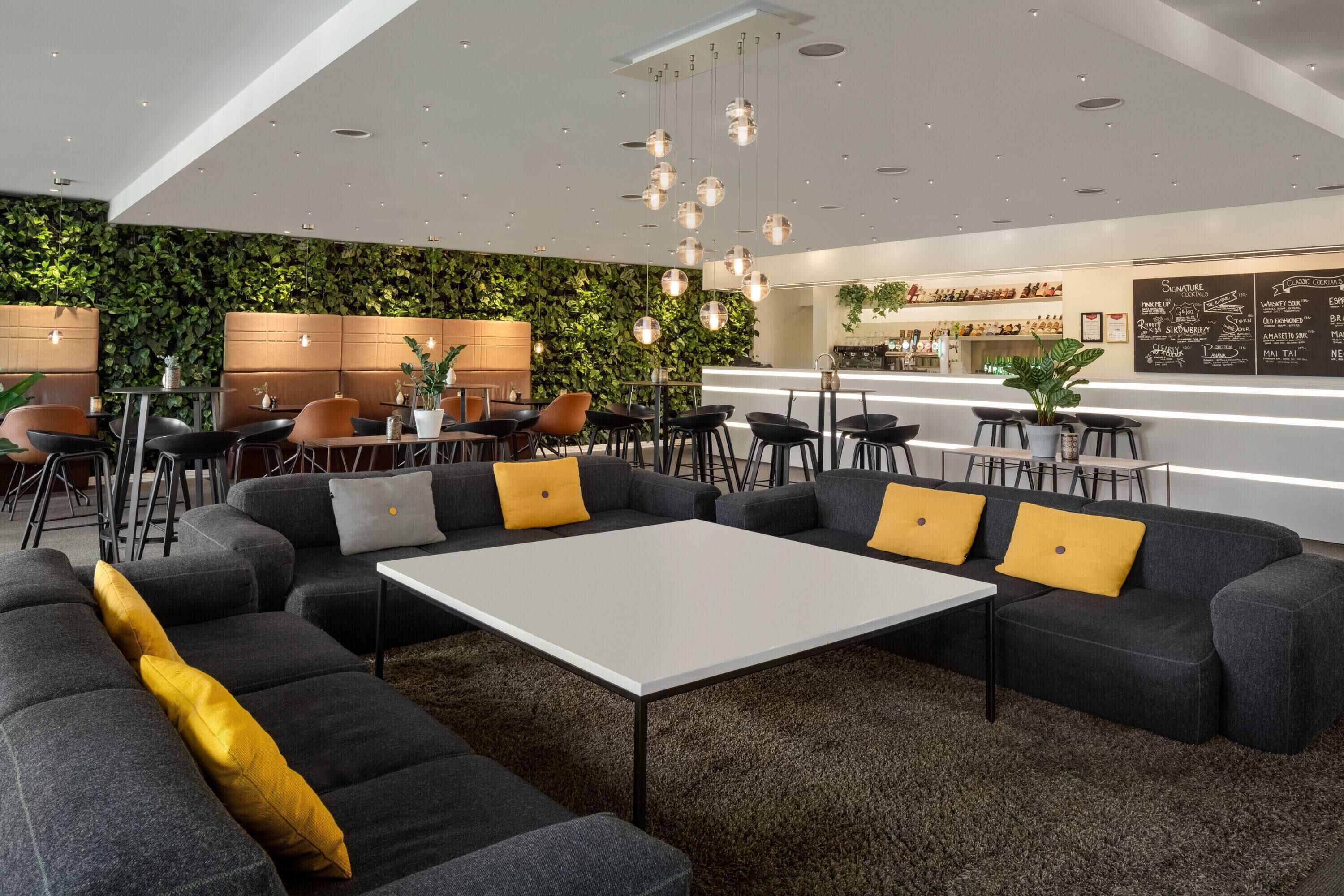 A modern lounge area with sofas, tables, and a bar counter.
