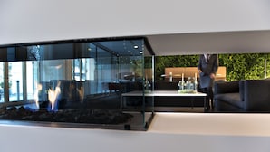 A modern interior with a glass partition, a seating area with a sofa and table, and a visible fire feature. - Comwell Hvide Hus Aalborg, Dolce by Wyndham (Aalborg)