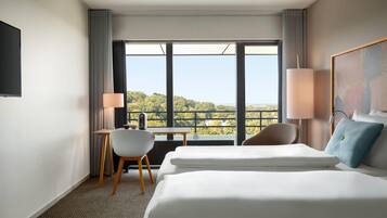 A hotel room with a large bed, a desk, a chair, and a view of the outdoors.