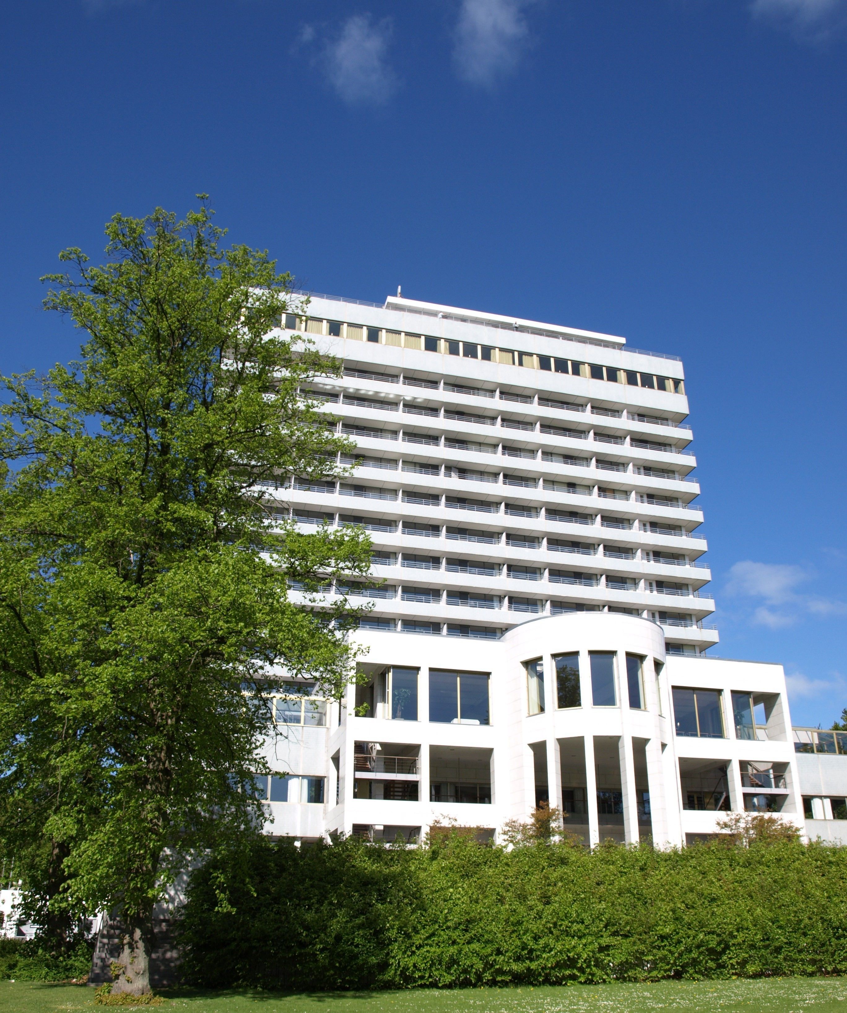 Un edificio de varios pisos con un estilo arquitectónico moderno, que presenta un techo plano y una fachada simétrica.