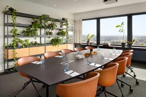 A conference room with a long table, multiple chairs, and a plant wall.