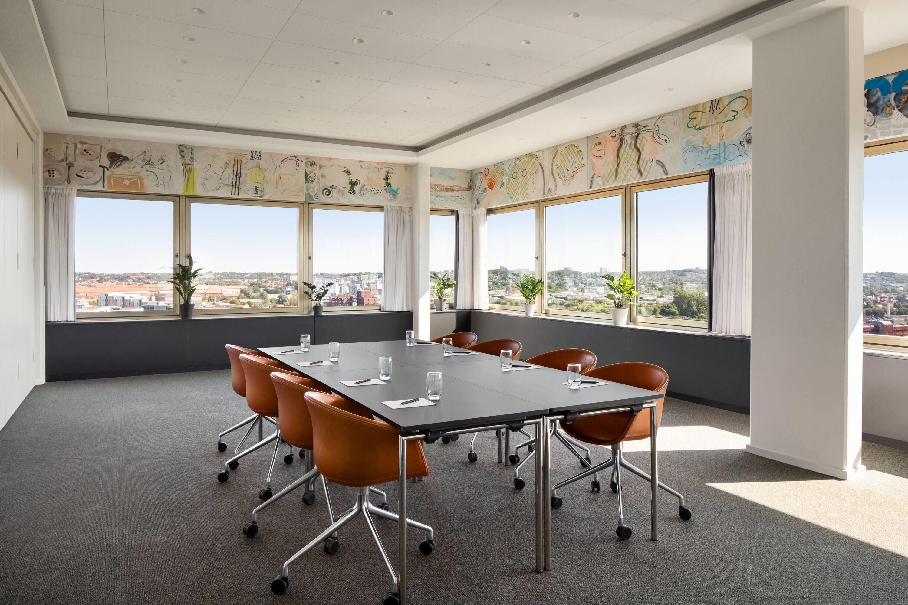A conference room with a large table, orange chairs, and large windows with city views.