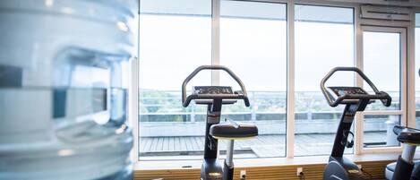 A gym with two stationary bikes and a large water bottle.