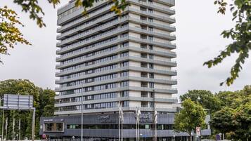 Een hotel met meerdere verdiepingen, voorzien van balkons, een restaurant en een parkeerplaats.