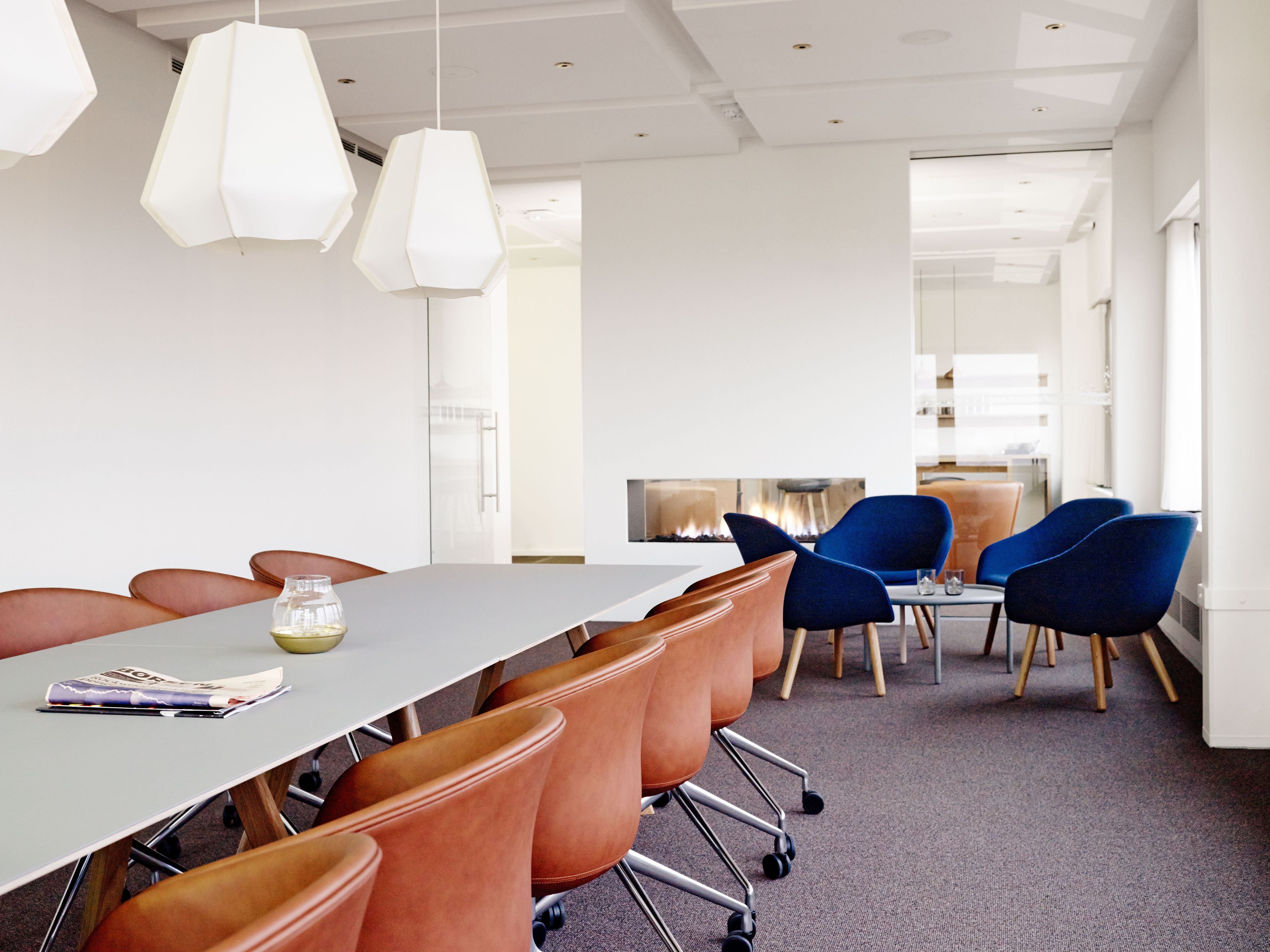 A modern conference room with a long table, orange chairs, and blue chairs.