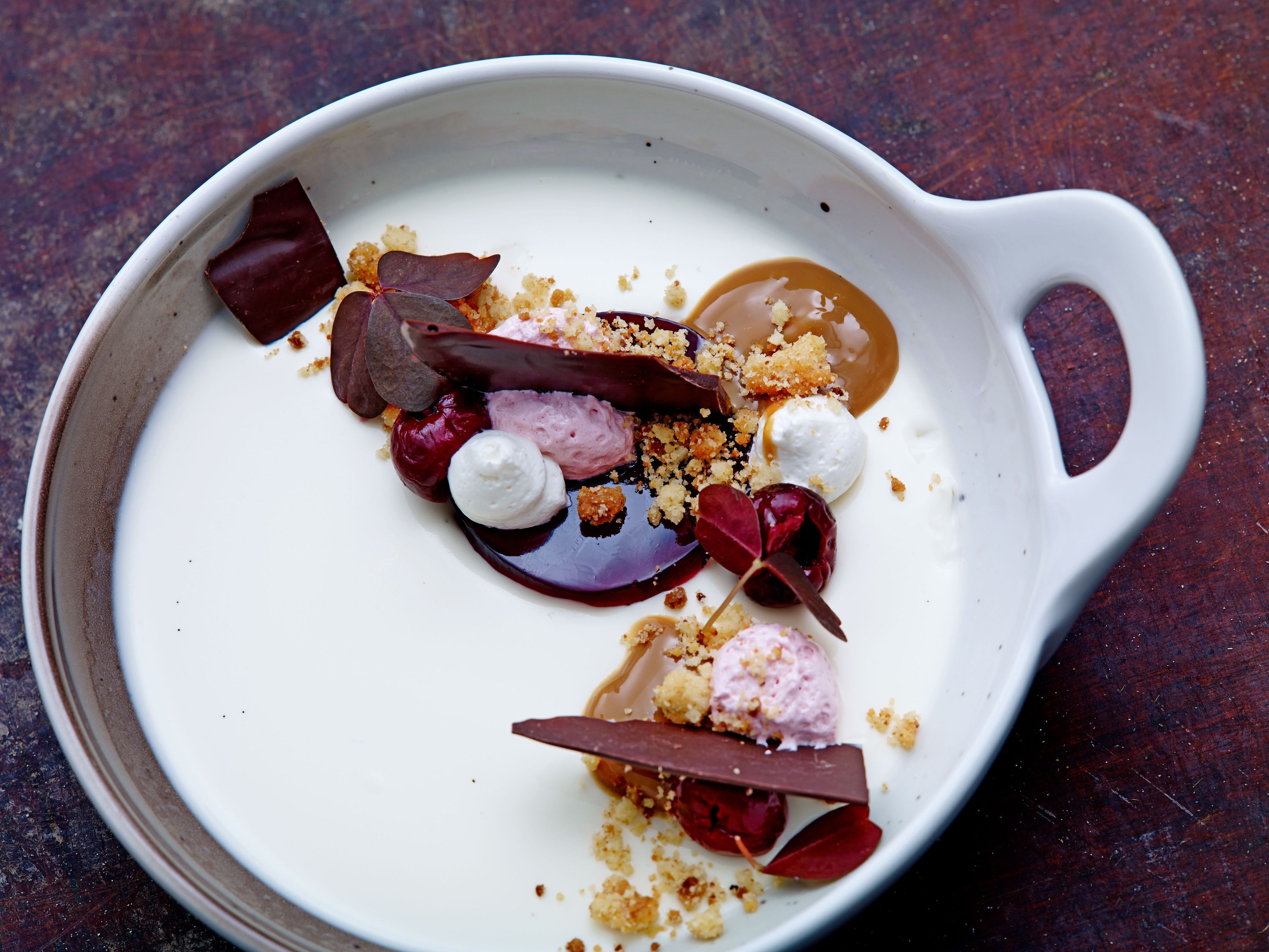 Un plato de postre con diferentes ingredientes y una bola de helado.