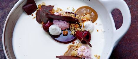 Un plato de postre con diferentes ingredientes y una bola de helado.