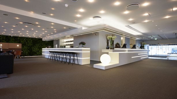 A modern reception area with a white reception desk, bar stools, and a green wall. - Comwell Hvide Hus Aalborg, Dolce by Wyndham (Aalborg)