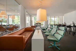 A modern conference room with a long white table, green chairs, orange sofas, and large pendant lights. - Comwell Hvide Hus Aalborg, Dolce by Wyndham (Aalborg)