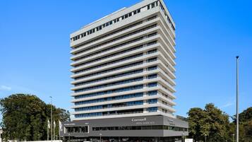 Un edificio moderno de hotel con varios pisos, techo plano y un cartel llamativo que dice 'Comwell Hotel Hvide Hus'.
