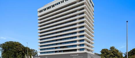 A modern hotel building with multiple floors, a flat roof, and a prominent signage for 'Comwell Hotel Hvide Hus'.
