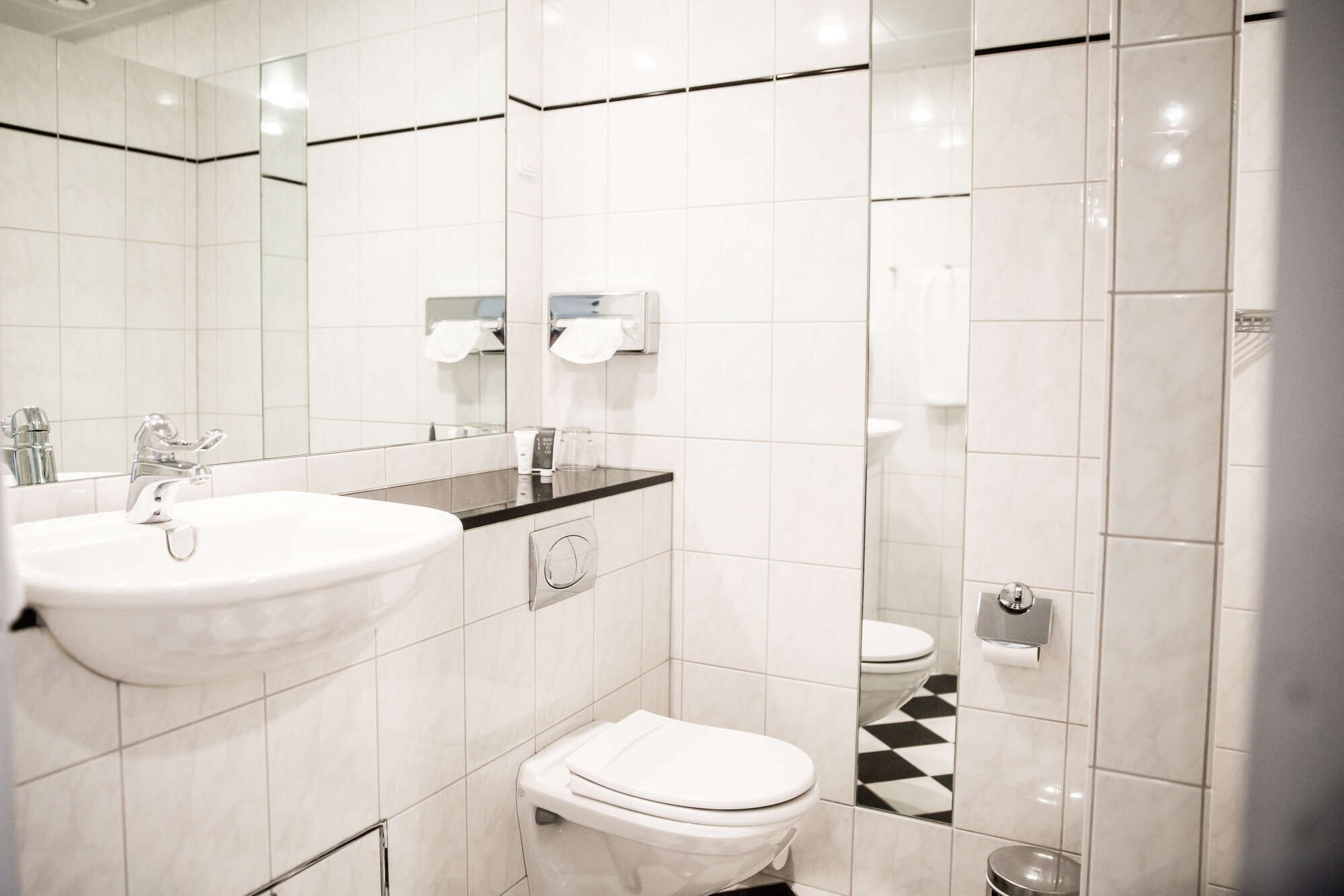 Un baño moderno con lavabo, espejo, inodoro y ducha.