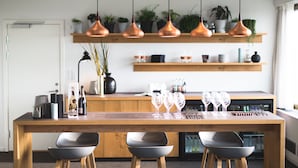 A modern kitchen with a wooden island, pendant lights, shelves with plants, and a refrigerator. - Comwell Hvide Hus Aalborg, Dolce by Wyndham (Aalborg)