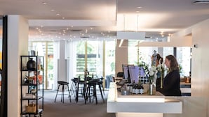 A modern reception area with a counter, seating area, and a bookshelf. - Comwell Hvide Hus Aalborg, Dolce by Wyndham (Aalborg)