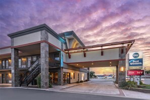 A hotel with a modern architectural design, featuring a prominent entrance, a staircase, and a sign indicating the name and temperature.