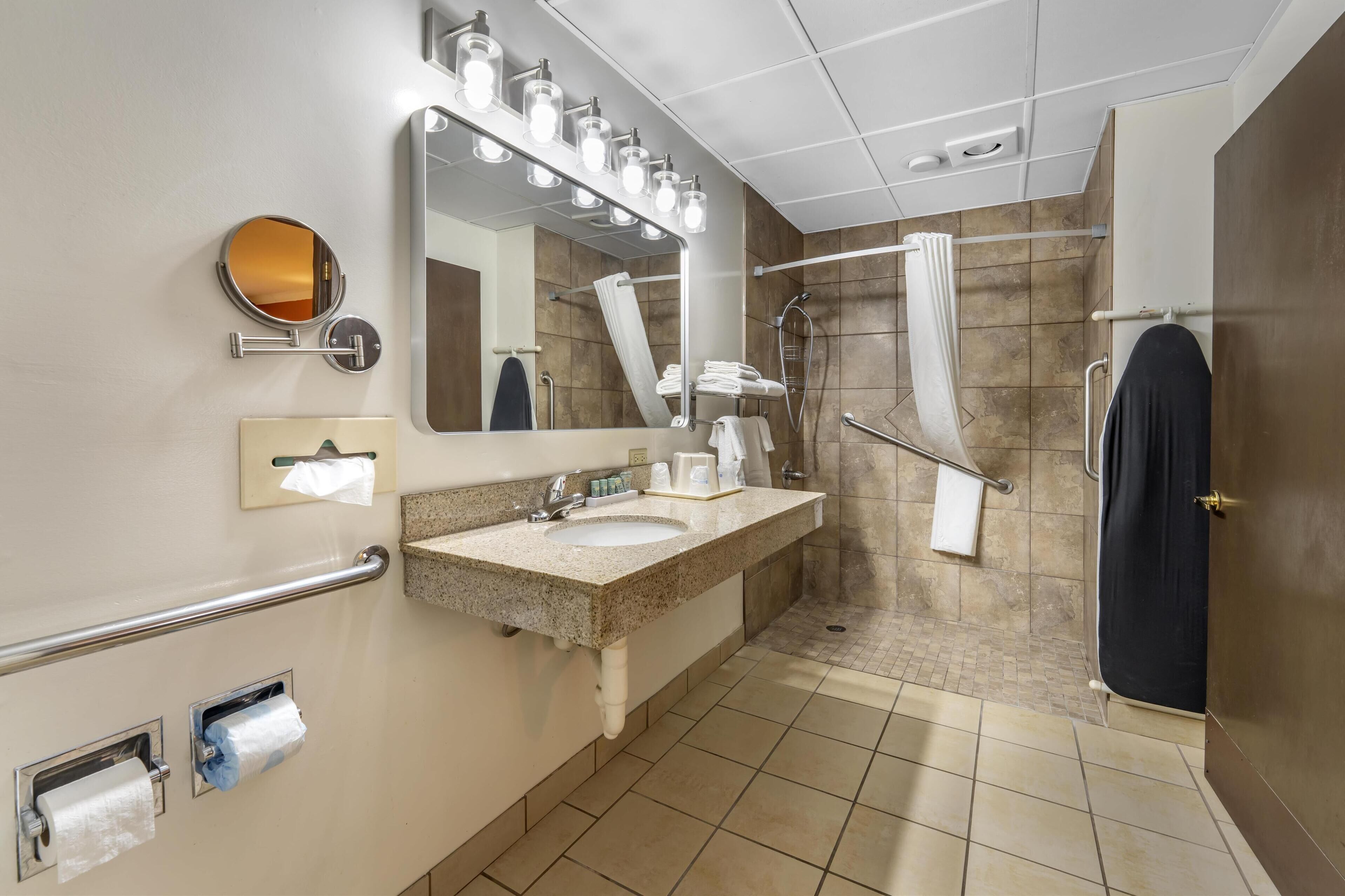 A modern bathroom with a sink, mirror, towel rack, and shower area.