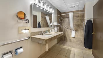 A modern bathroom with a sink, mirror, towel rack, and shower area.