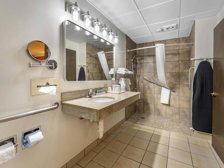 Un baño moderno con lavamanos, espejo, toallero y zona de ducha.