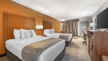 A hotel room with two beds, a desk, a chair, and a television.
