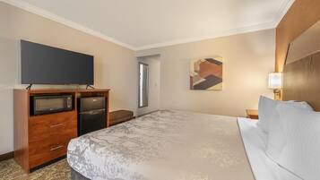 Una habitación de hotel con una cama grande, un televisor de pantalla plana, un microondas y un refrigerador.