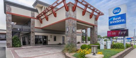 A Best Western hotel with a covered entrance, stone pillars, and a digital sign displaying the time and temperature.