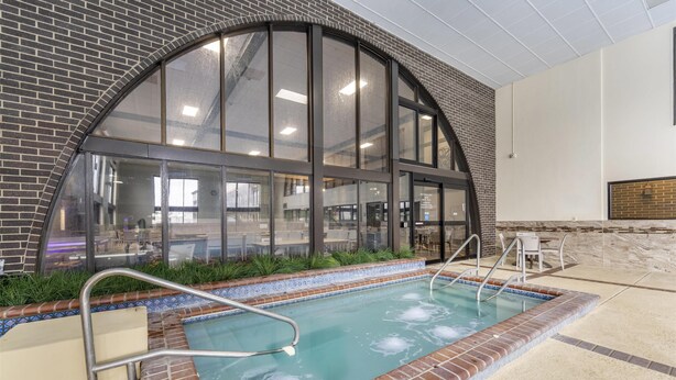 Une piscine intérieure bordée de briques, dotée de grandes fenêtres et offrant une vue sur l’espace intérieur.