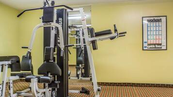 A gym with various exercise machines, a patterned carpet, and a poster on the wall.
