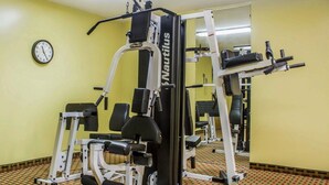 Une salle de sport équipée de machines Nautilus, avec une horloge et un sol à motifs.